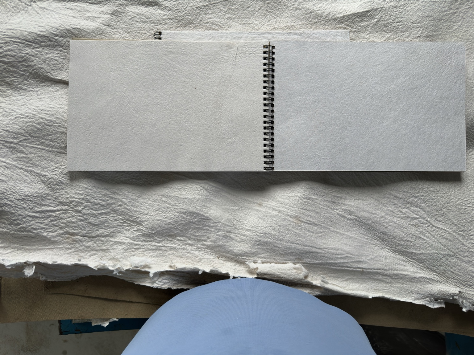 An open bound notebook showing its textured handmade pages