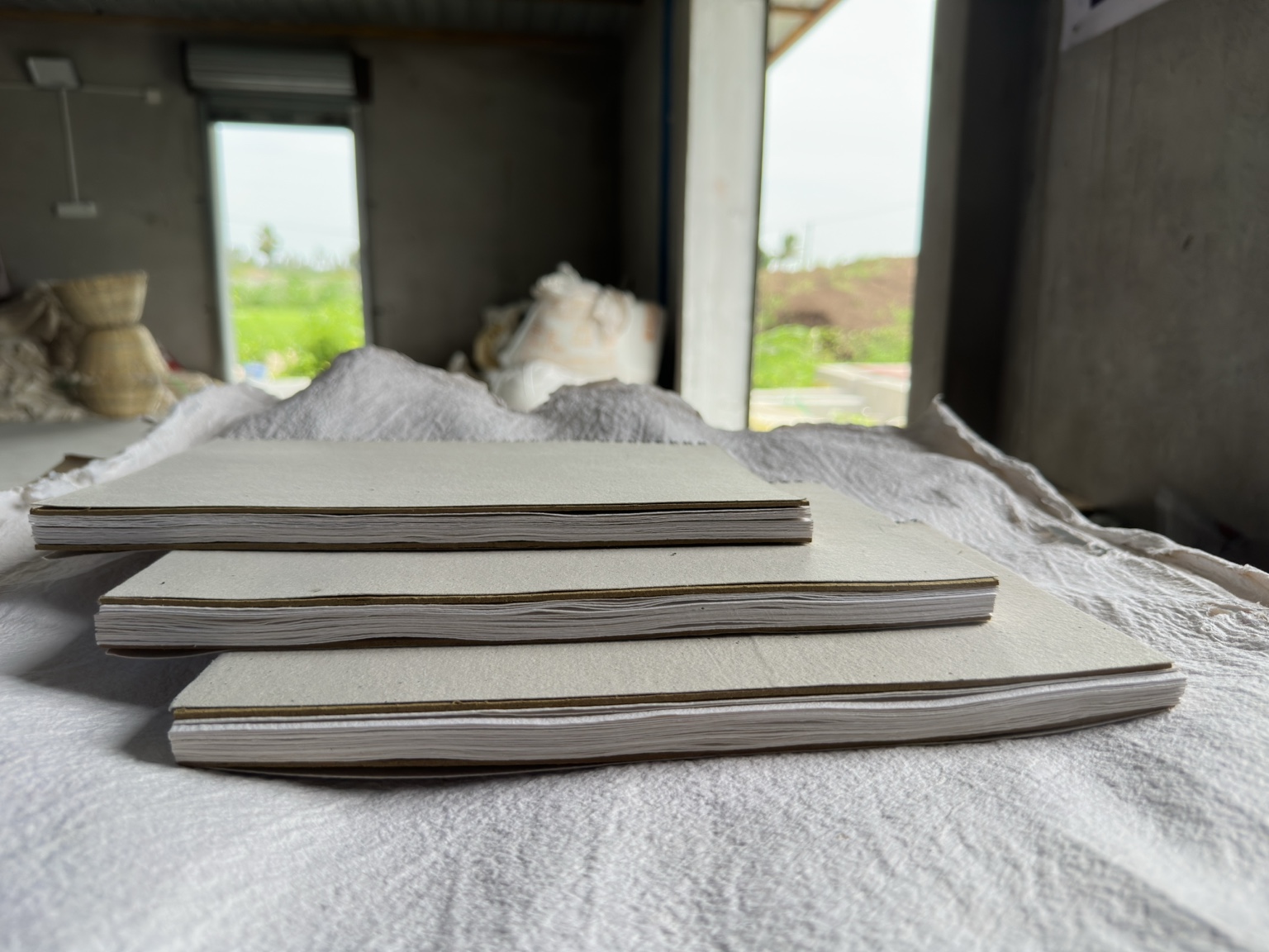 A stack of handmade paper notebooks held in the workshop