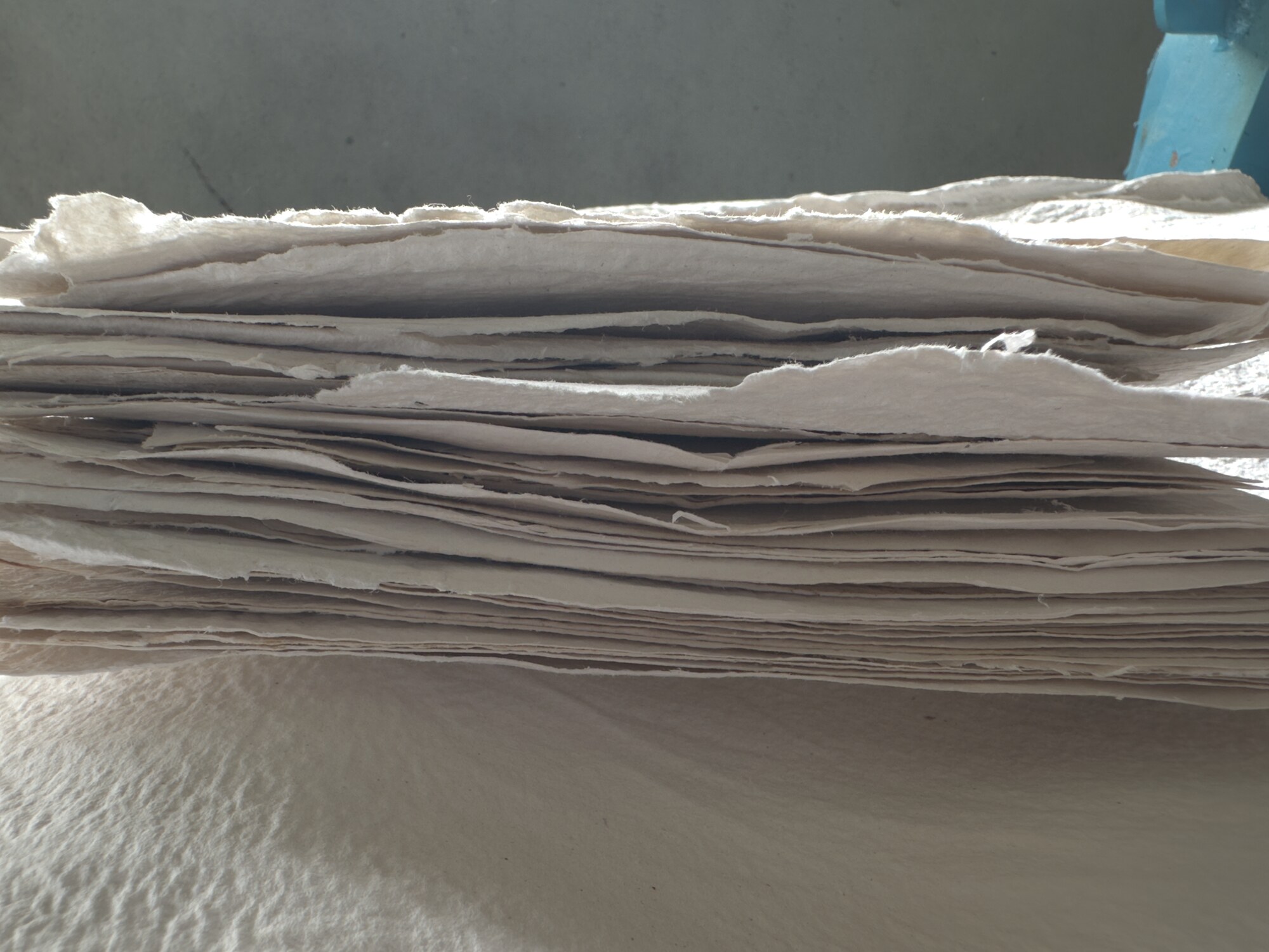 A stack of handmade paper sheets with deckle edges in the workshop